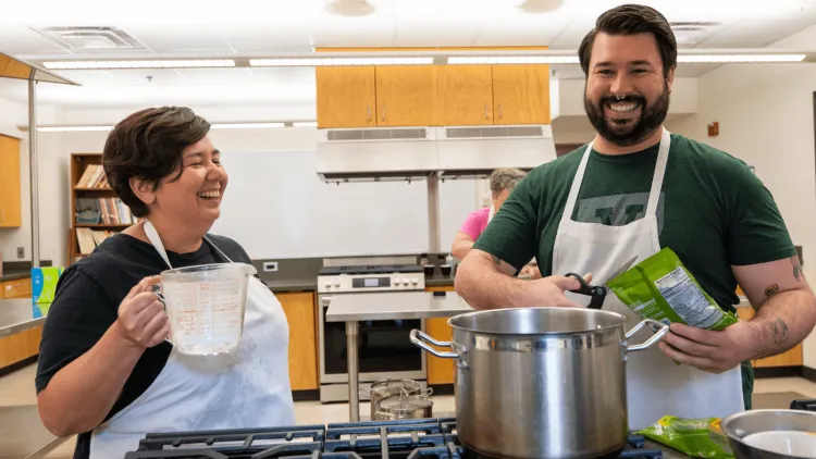 Alexis Yamashit and Brian Griffith smiling over a cook pot