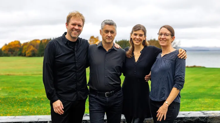 Four people standing side by side outdoors