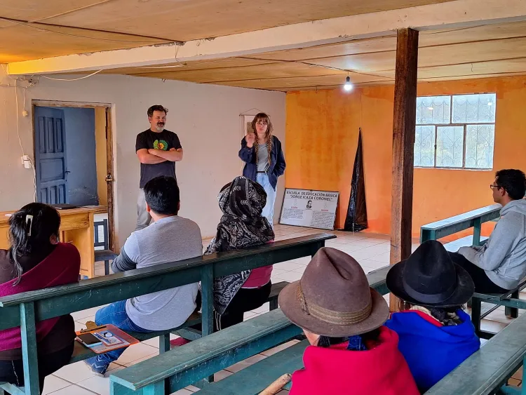 two people stand in front of a room speaking with folks sitting