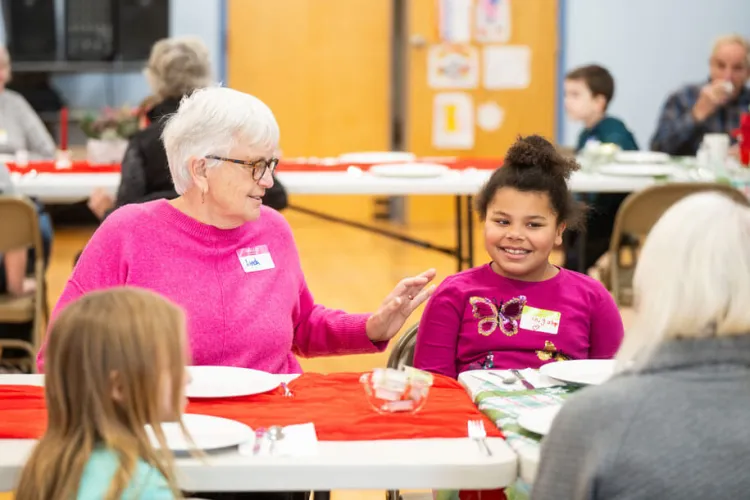 a senior smiles at an elementary student during lunch