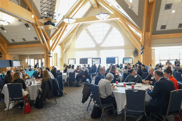 a large crowd sitting at tables at an academic meeting