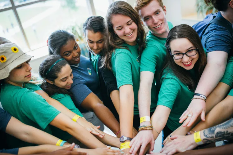 Students place their arms int he center for a group cheer