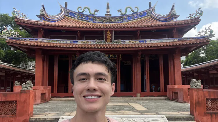 Smiling person taking a selfie in front of an temple.