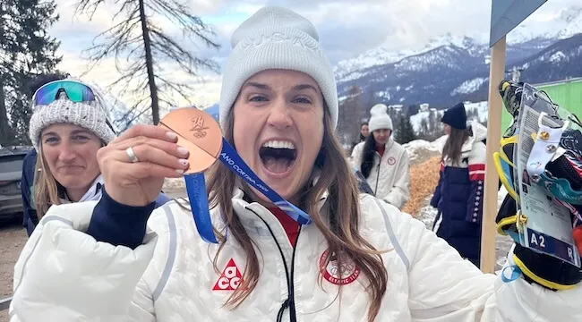 a women holds up her bronze Olympic medal