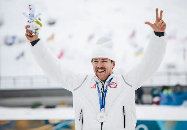 an Olympic medalist at his award ceremony holds his hands in the air