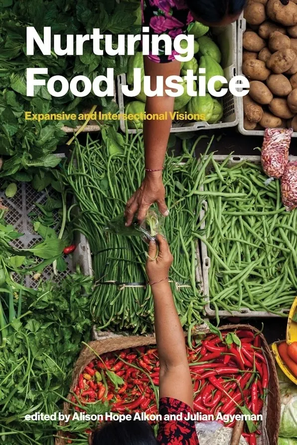 A book cover showing hands reaching toward one another over bins of veggies like peppers, beans and potatoes. The title is "Nurturing Food Justice."