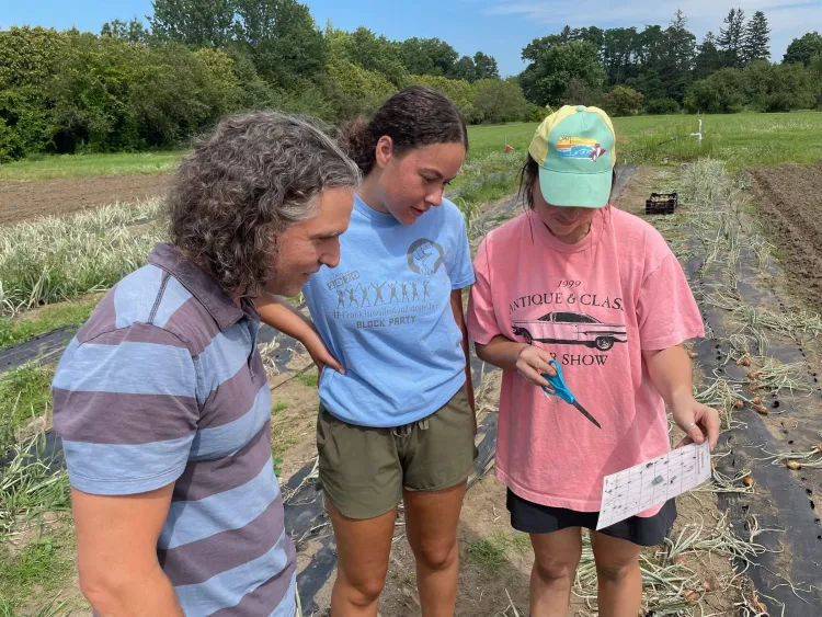 three people in a field looking at a piece of paper