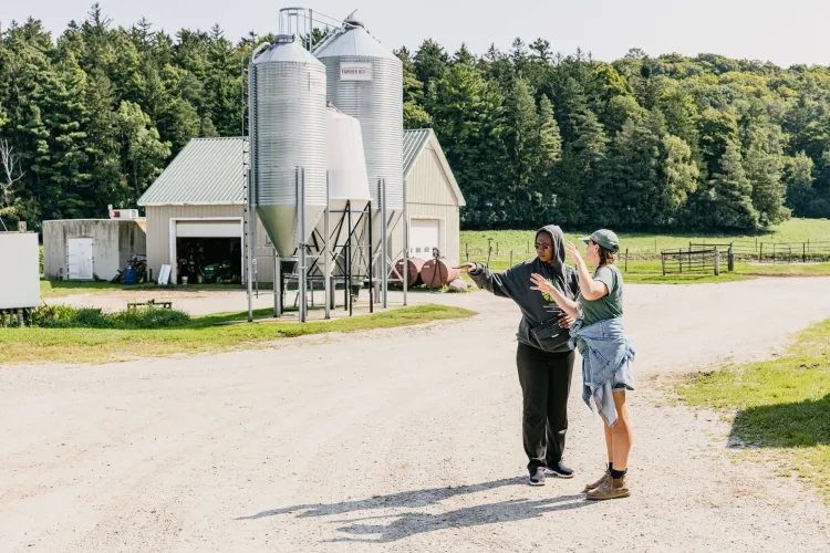 two people talking in front of a dairy barn