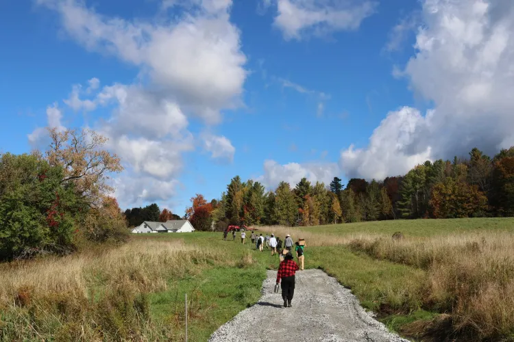 people walk down a gravel road toward a farm house