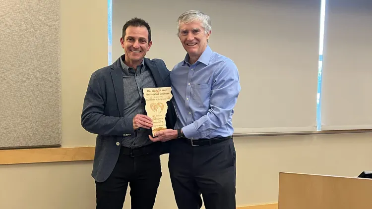 Dr. Quintana and Dr. Francisco holding a plaque shaped like the state of Vermont.