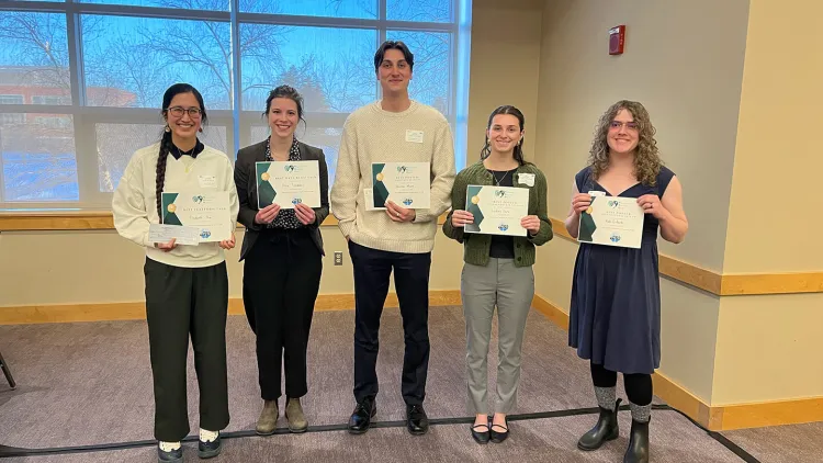Five individuals stand with certificates in their hands.