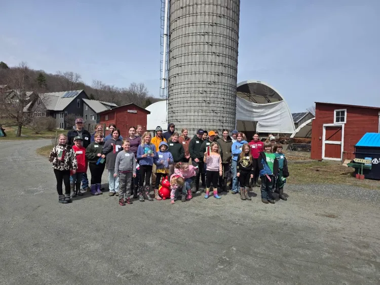 Many youth stand outside at a farm. 