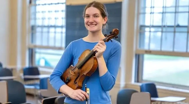 a women posing with a violin in her hands