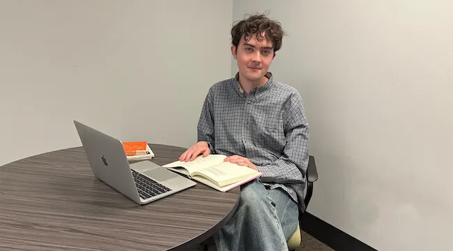 a young man sitting at a table with a laptop