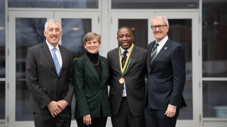 a group of people, one wearing a medal, standing in front of a building entrance