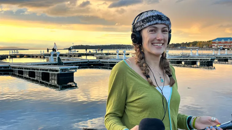 young woman in green sweater with audio equipment at Burlington lakefront