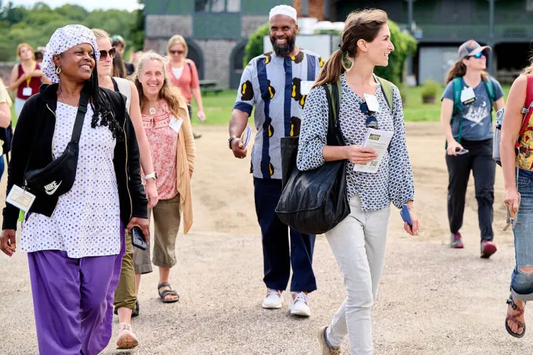 Many people walking and smiling outside on a sunny day.