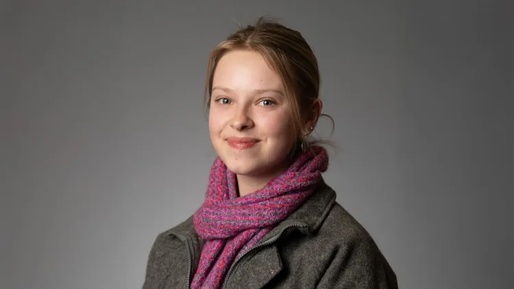 Person smiling at the camera against a plain background.