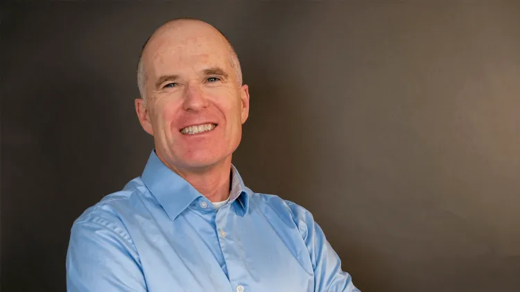 Person smiling at the camera against a neutral background.