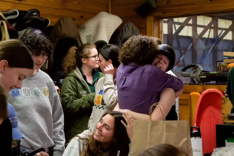 Two people hug in a crowd of young adults all looking relaxed