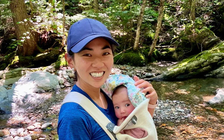person holding a baby on their chest while on a hike