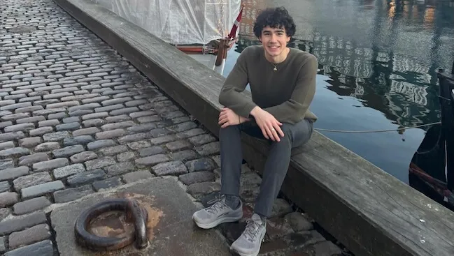 a young man sitting on a waterfront dock