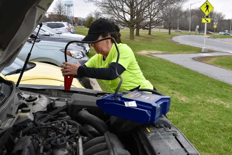 A parking officer jumpstarting a student's car on campus
