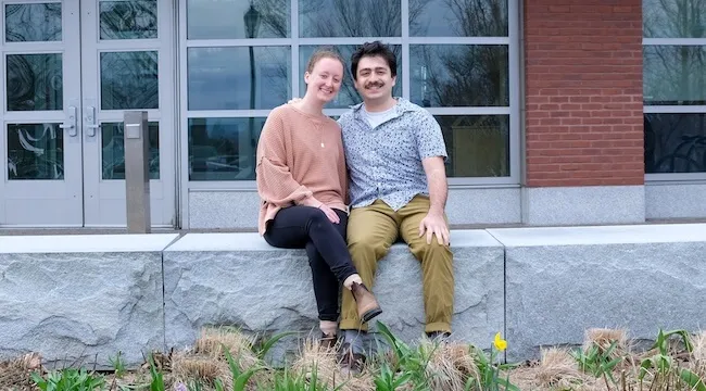 a man and a woman sitting in front of a brick building
