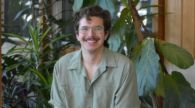 a man sitting in front of large green plants