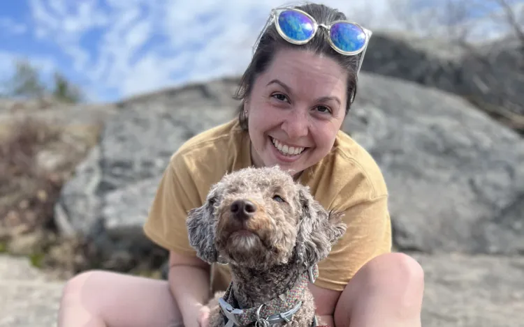 smiling person and a content dog sitting on a rock enjoying a summer day