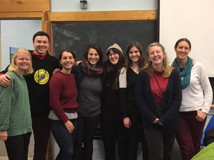 Eight people stand together and face the camera