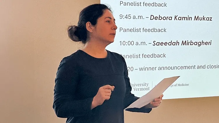 a person presenting research in front of a screen showing a slide