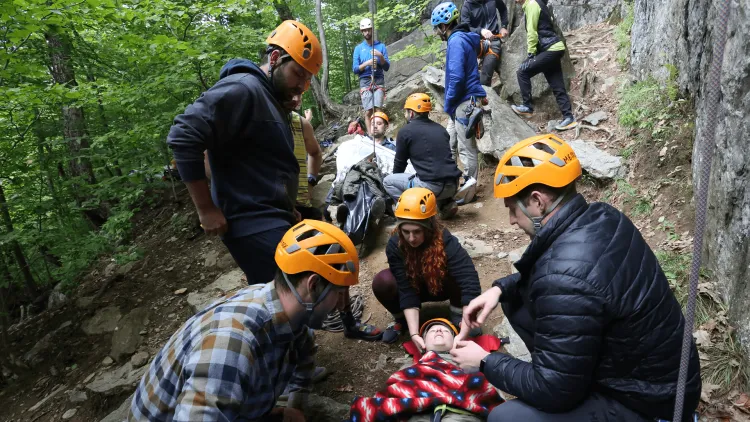 a group of people wearing helmets in an outdoor wilderness medicine class