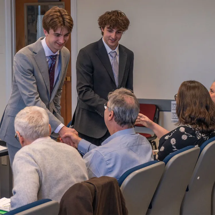 Students shake hands with the seated judges at the UVM Business Pitch Competition
