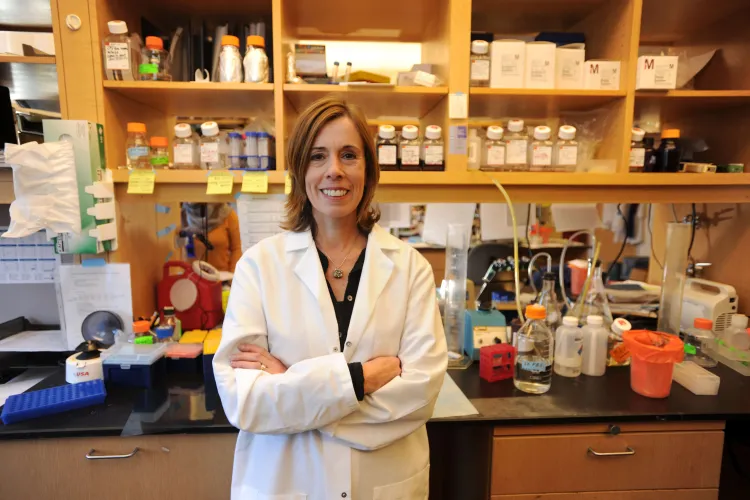 Peron in a lab coat in a lab setting smiling at the camera. 