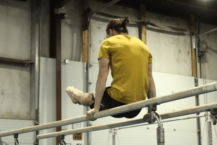 A young man doing gymnastics on the parallel bars 