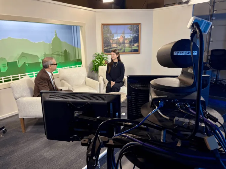 A young woman sitting with the host of Across the Fence in a TV studio