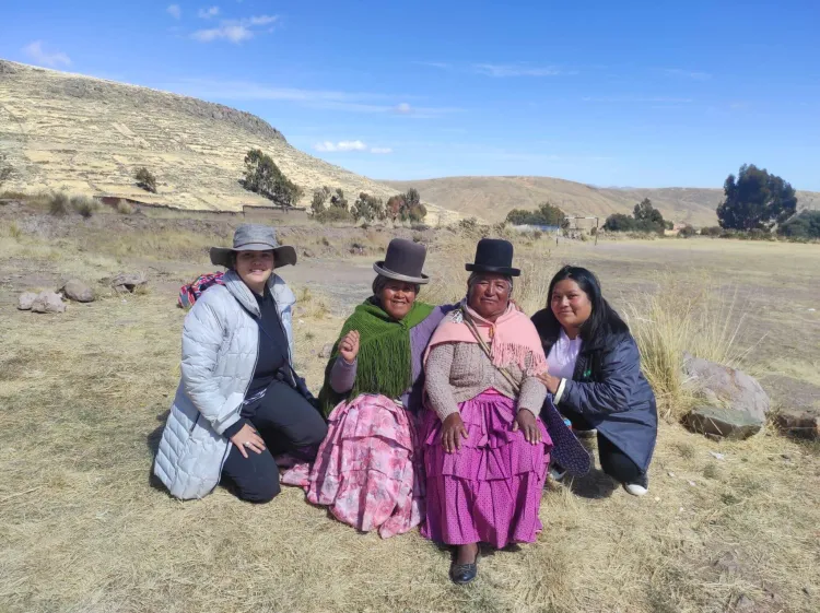 Four people sit with mountains in the background.