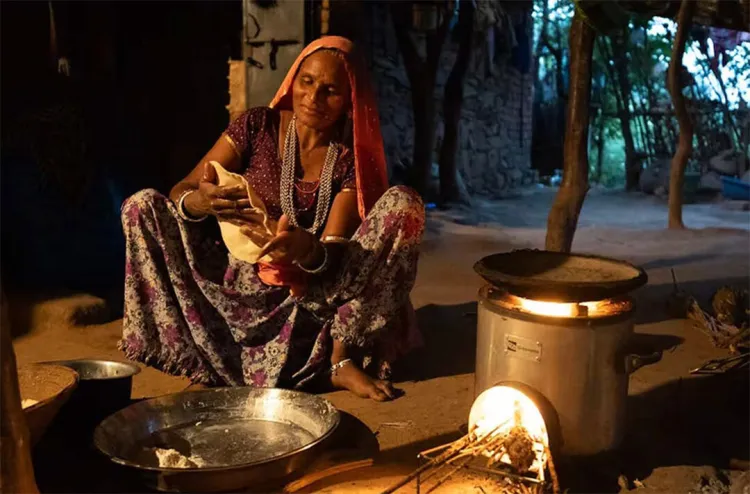 A woman in India sits while making food.