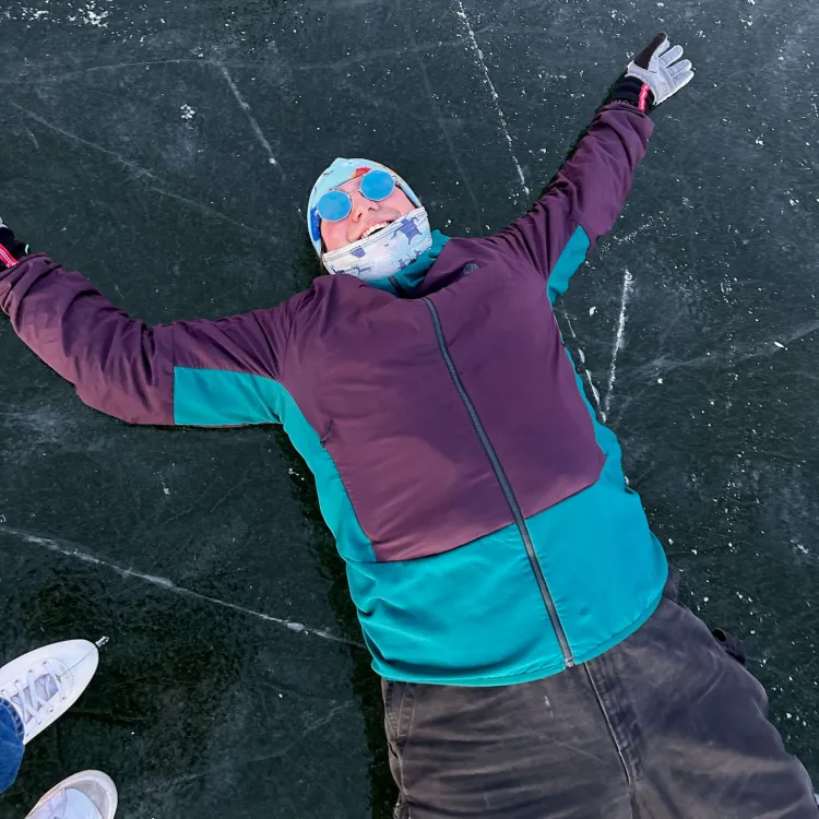Carlos laying down on the ice of a skating pond.