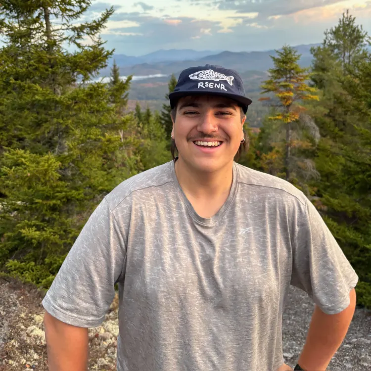 Carlos in a RSENR hat on top of a mountain.