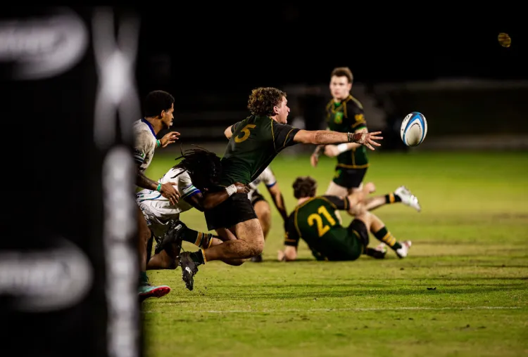 A man playing rugby with the ball just out of reach in the air