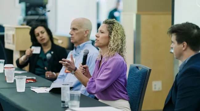 a women speaks into a microphone at a panel discussion