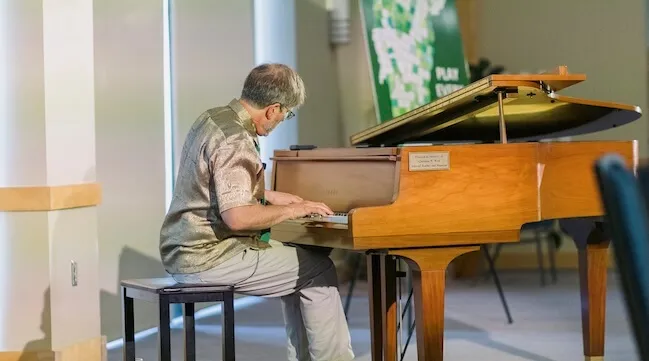 a man playing a baby grand piano