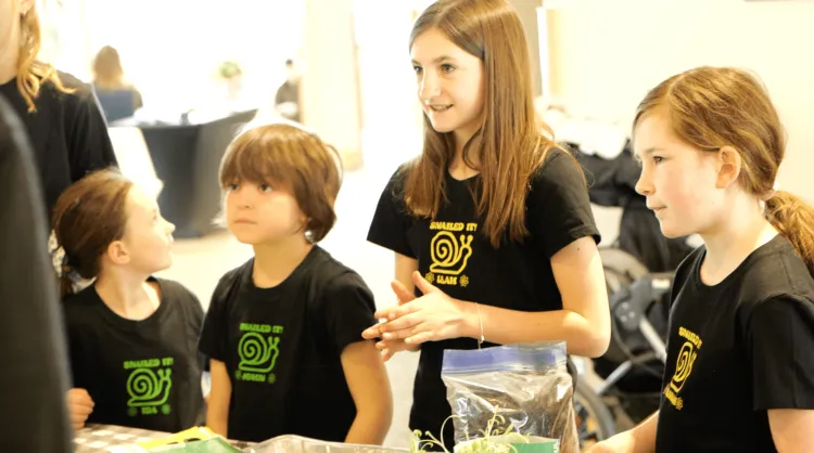 Four young people wear matching black shirts that read "Snailed it!"