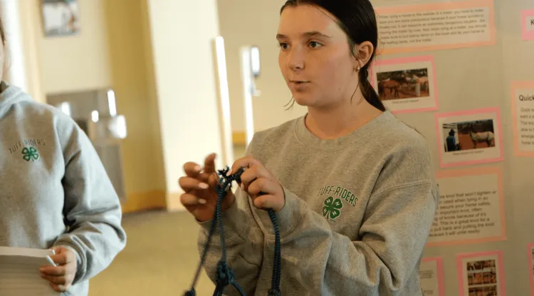 A young person holds rope and speaks.
