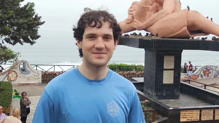 Smiling young man in blue t-shirt with ocean and statue in background
