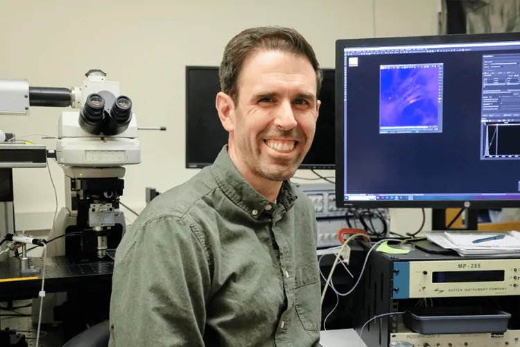 Man in a science lab smiling at the camera. 