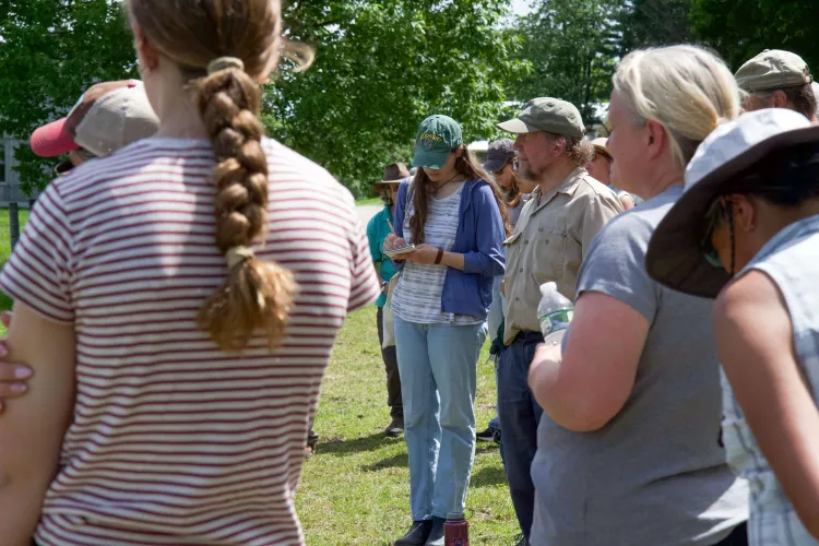 A group of people, with the focus on a young person in the center taking notes