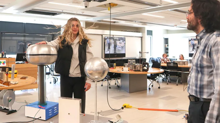A student participates in a "hair-raising" physics demonstration.